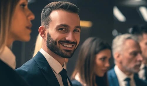 A smiling in-house lawyer in a suit, next to his legal department. Bigle Legal CLM article on legal tech.