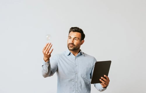 Lawyer with a tablet holding a light bulb while looking at it. Sustainability and CLM article by Bigle Legal.
