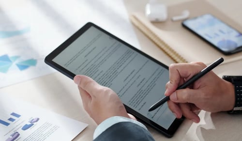 Hands of a lawyer in a suit signing a document on a tablet. Electronic signature article by Bigle Legal.