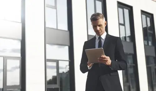 Lawyer outside his office consulting a tablet. Bigle Legal article on compliance and CLM.