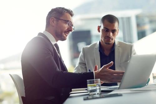 Lawyers in suits chatting in front of their computers in an office. Article by Bigle Legal CLM.