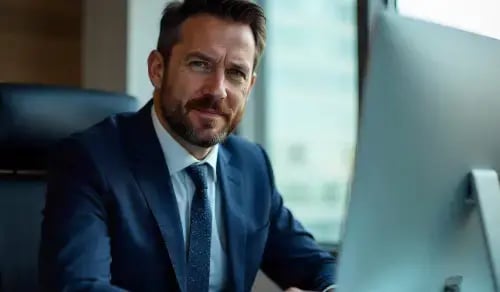 Photograph of a lawyer in a suit looking at the camera while working at his computer. Article by Bigle CLM.