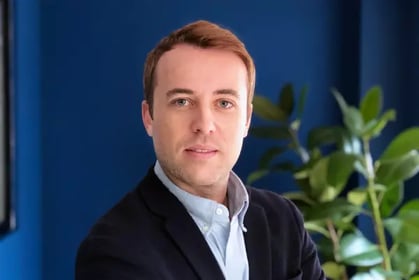 Photography of Sergio Esteve de Miguel with a blue wall and a plant in the background.