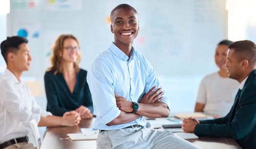 Smiling team leader leaning on his desk with his arms crossed. 6 tips from Bigle Legal to improve your legal department.