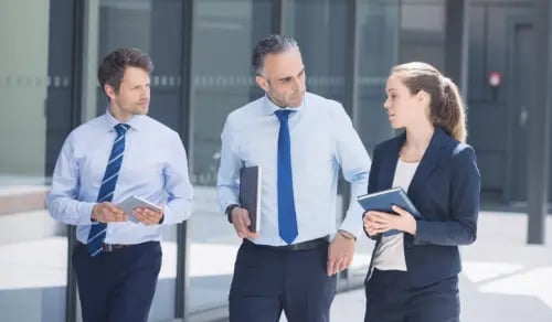 Three lawyers chat next to their glassed-in office with their diaries in hand. Bigle Legal article on legal tech.