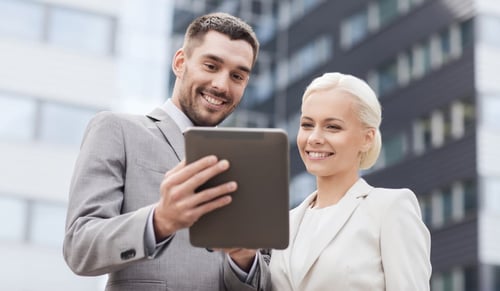 Two young lawyers look at a tablet and smile