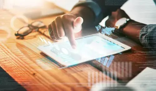 Young lawyer works on his contract on a tablet on a wooden table. Bigle Legal article on Contract Management.