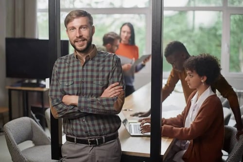 Joven abogado con una camisa de cuadros, sonriente y de brazos cruzados. Artículo de Bigle Legal sobre project management.