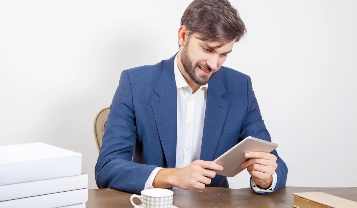 Smiling lawyer looks at his mobile phone sitting in his office, Bigle Legal article on entertainment.