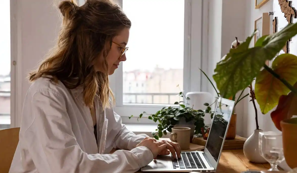 Young woman teleworks from her living room with her laptop. Bigle Legal article on telework and ESG.