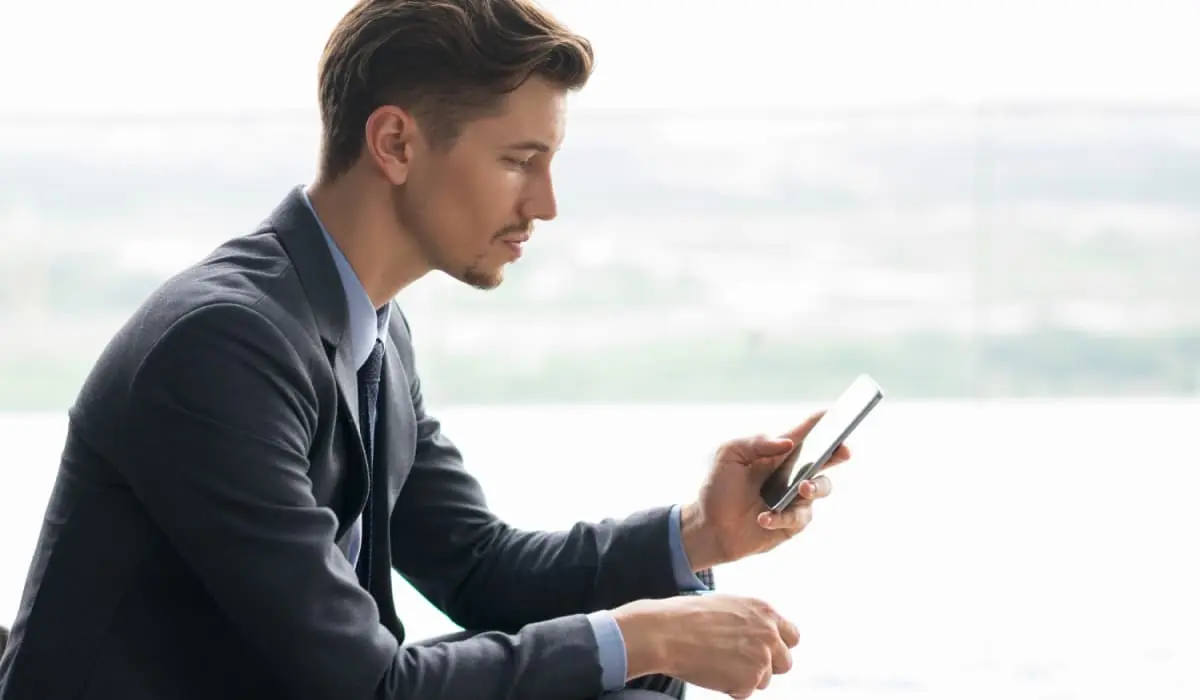 Suited man consults his phone behind a rising graph. Bigle Legal article on legal tech trends in 2021.
