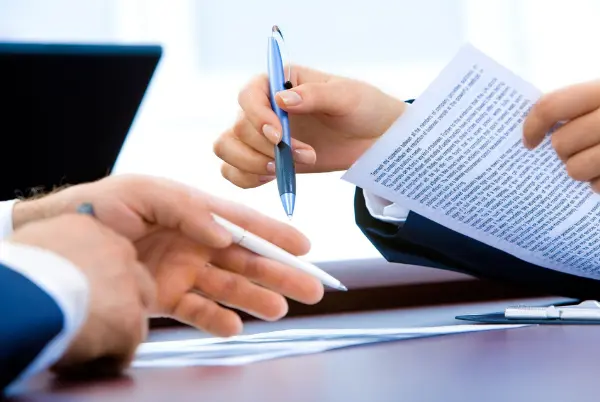 Lawyers holding a document in a meeting. Bigle legal article on contract management.