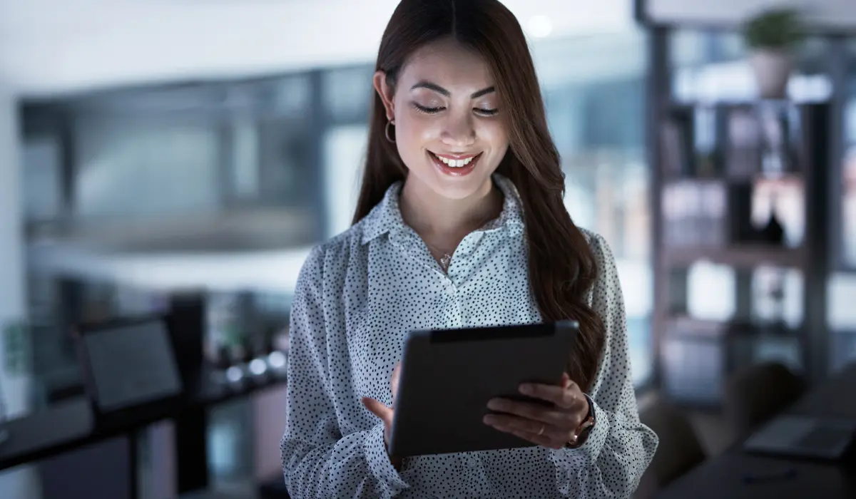 Mujer sonriente consulta su tablet, artículo de Bigle Legal sobre cómo digitalizar un negocio.