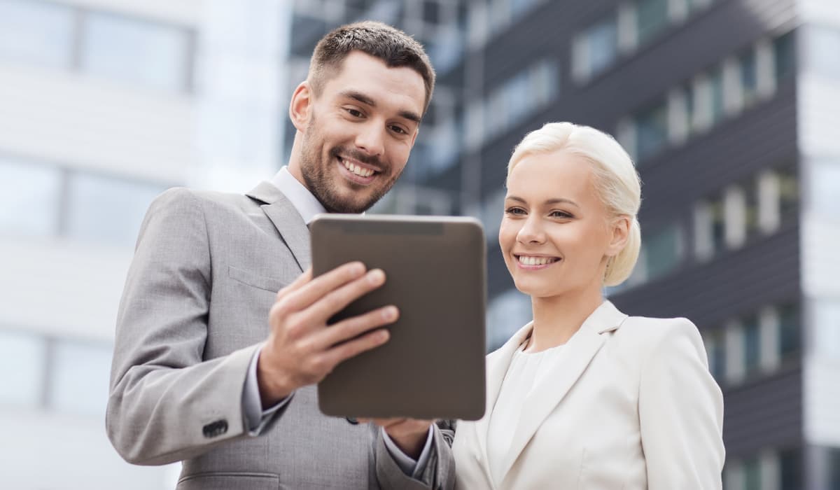 Two young lawyers look at a tablet and smile. Compliance automation article by Bigle Legal.