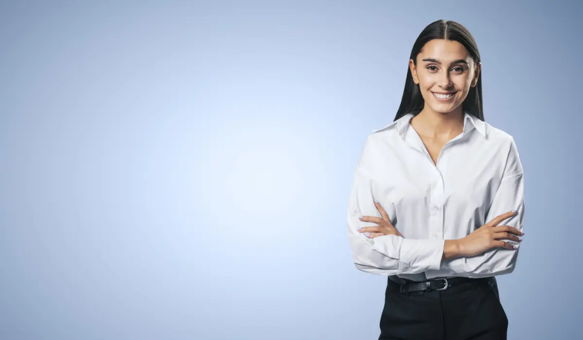 Young lawyer with arms crossed and smiling, on a grey background. Article on companies and legal tech by Bigle Legal.