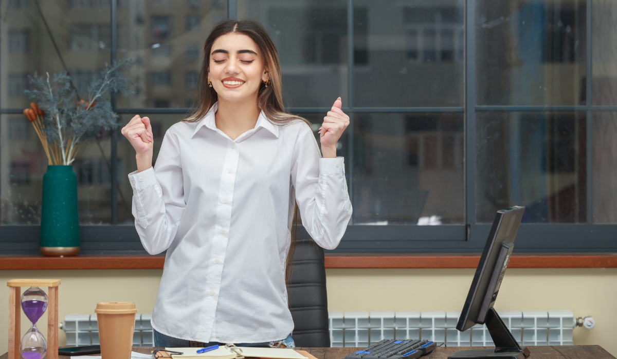 Trabajadora aprieta los puños sonriente, artículo de Bigle Legal sobre actitud y productividad.